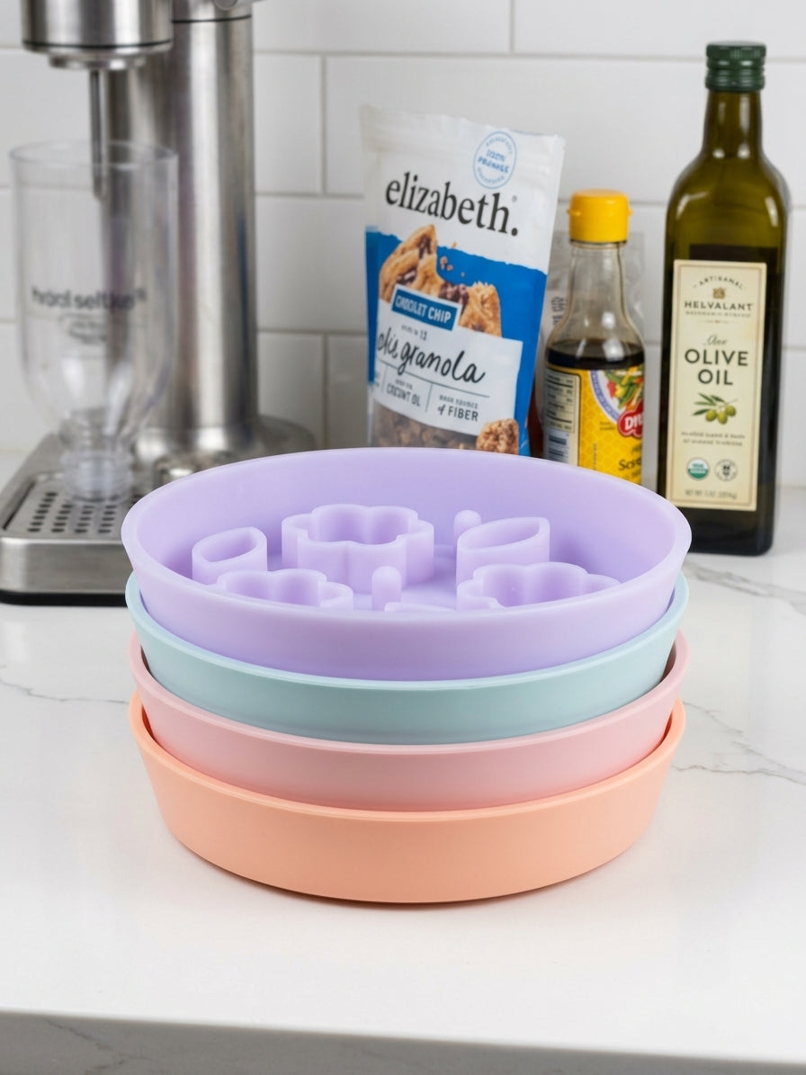 Purple, blue, pink and peach slow feeder bowls stacked on a kitchen counter.