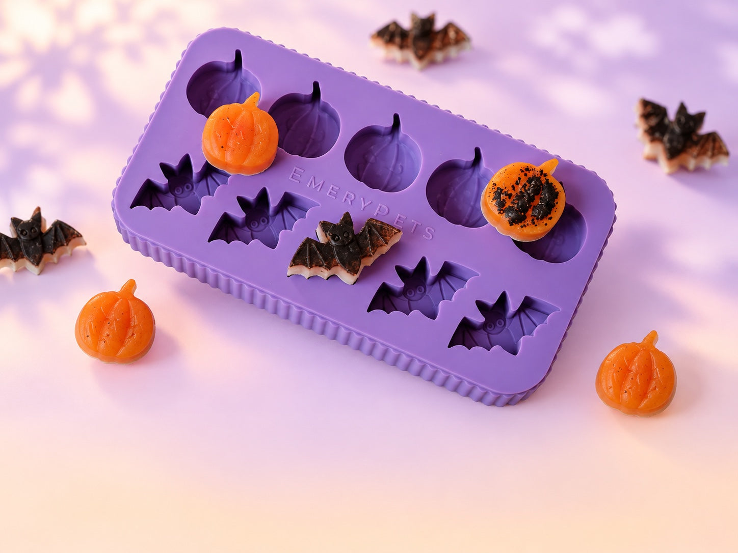 Purple Bat + Pumpkin treat mold with orange pumpkin and dark bat treats on a pastel lavender background